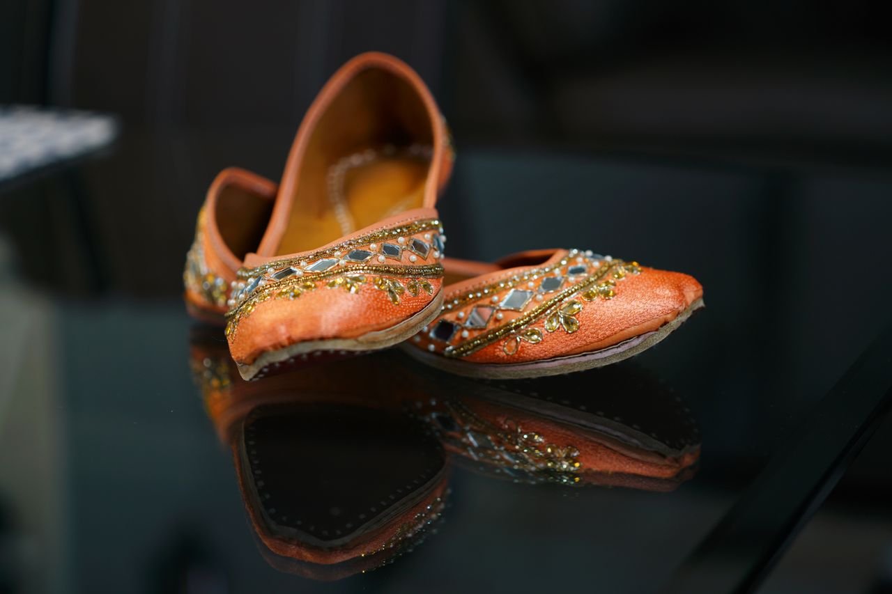 Elegant pink bridal ballet flat shoes in oriental style decorated with crystals and arranged on glass table
